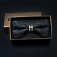 Men's dark patterned bow tie with metal bar rings at center, shown in box