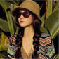 Striped straw topee hat worn with sunglasses and a colorful patterned top