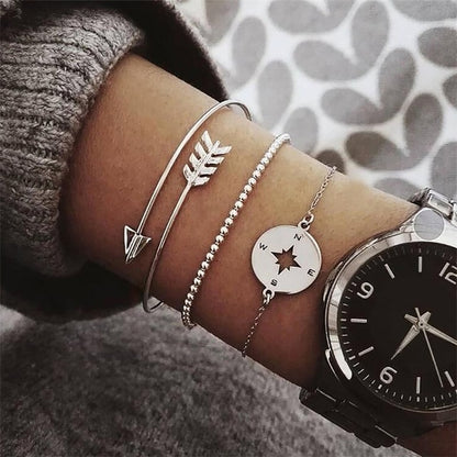 Silver-toned bracelet set with arrow and leaf charms plus round compass charm, on wrist