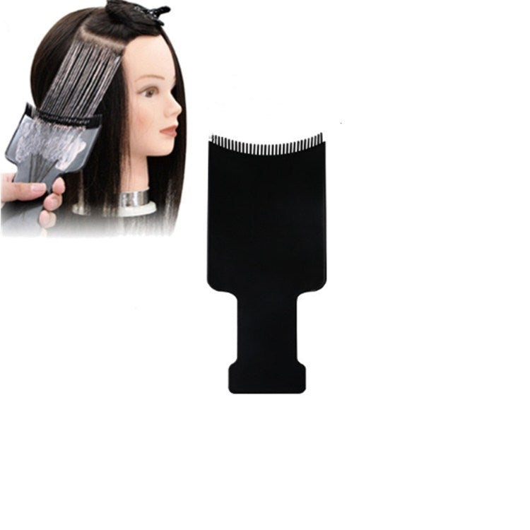 Hair dye applicator brush with black comb edge, held to apply color to hair
