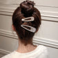 Two rhinestone hair barrettes with pearl accent on a bun hairstyle