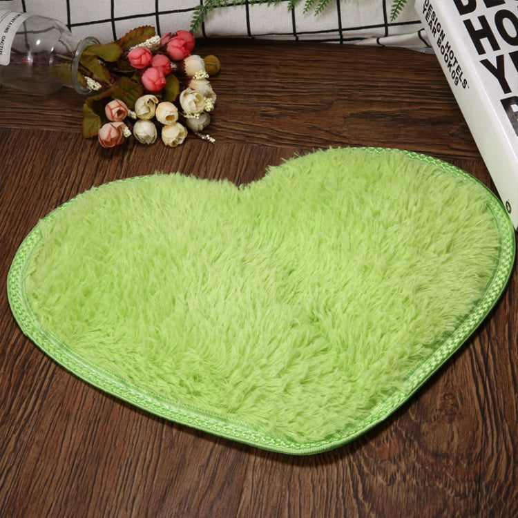 Light green heart-shaped bath mat with textured pile and non-slip edge binding.