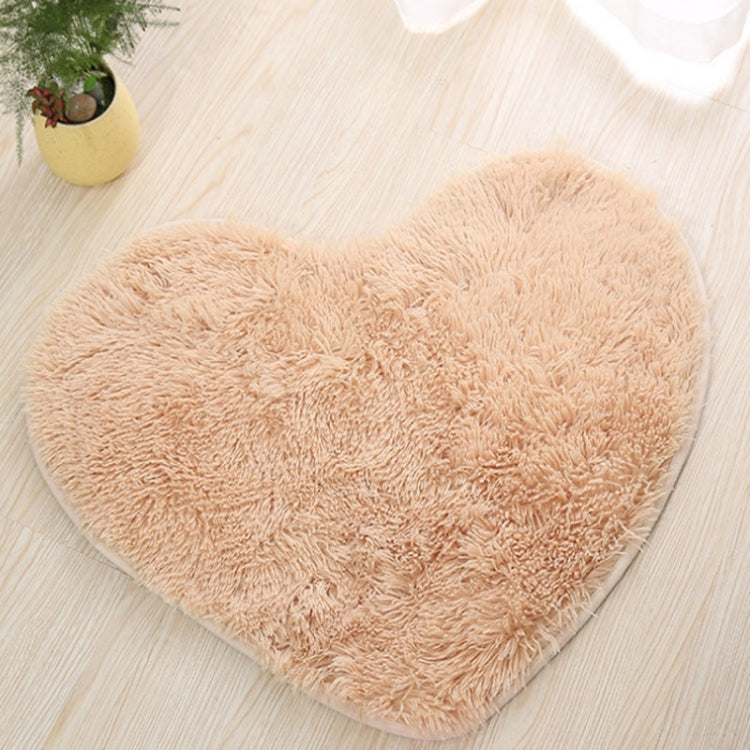 Beige heart-shaped bath mat with fluffy shag texture and non-slip edge trim.