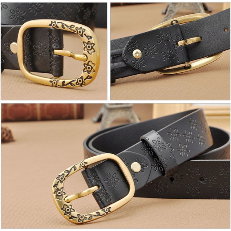 Black PU leather belt close-up: embossed flower details with gold buckle prong