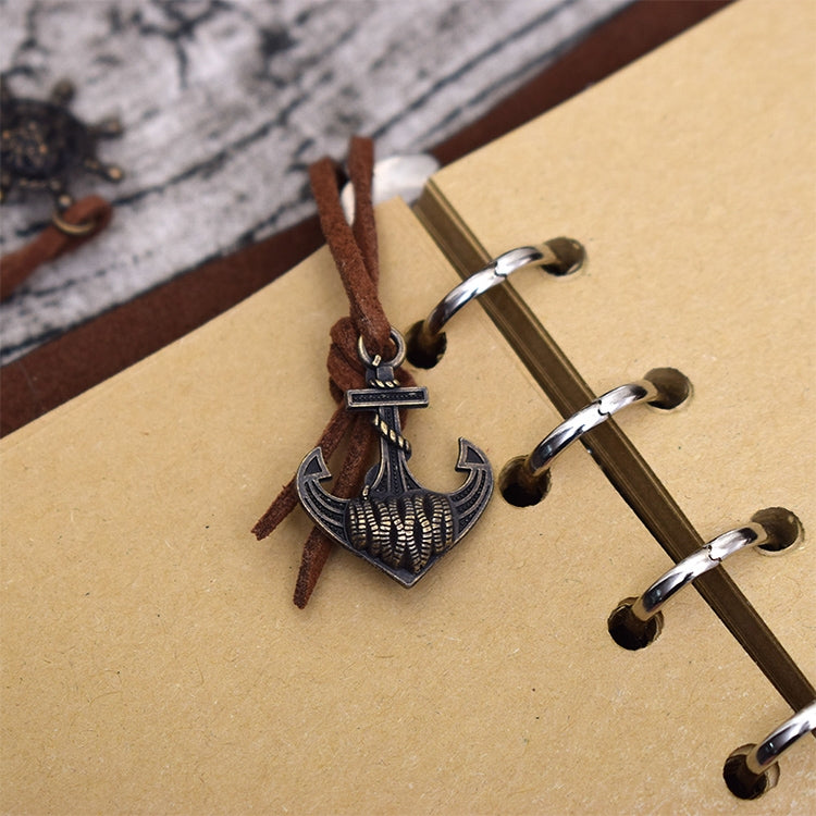 Close-up of pirate charm clasp and spiral rings on a kraft paper notebook journal