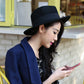 Navy wide-brim wool hat with black band, worn by a woman outdoors.