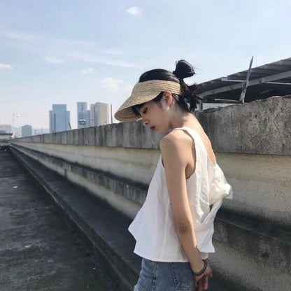 Woven straw visor hat with wide brim and dark headband, worn with tie-back.