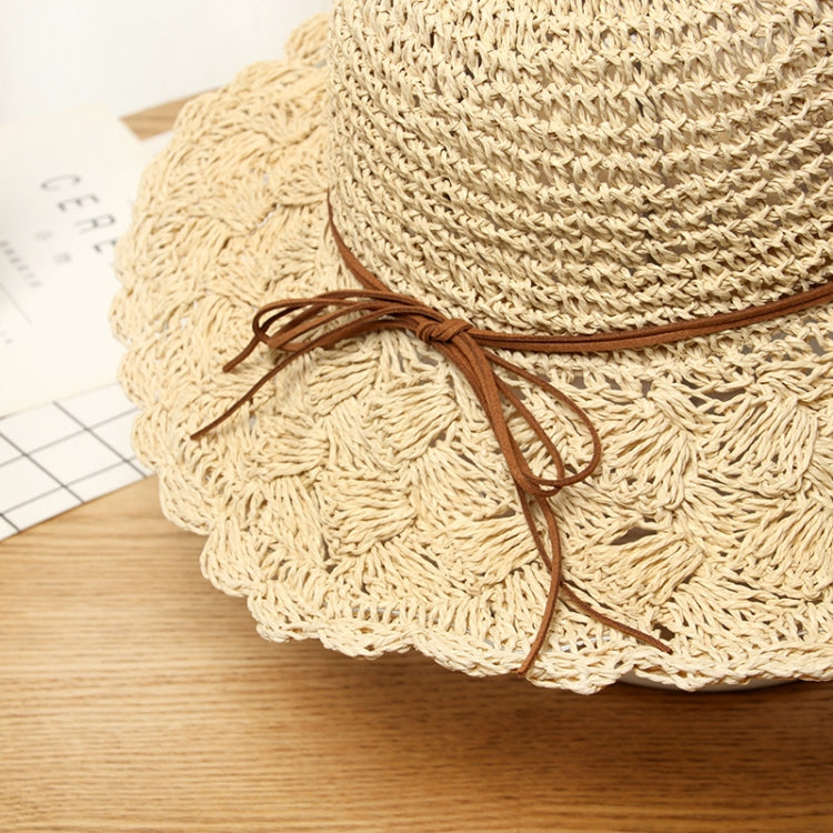 Close-up of beige woven straw sun hat with brown ribbon tie at brim
