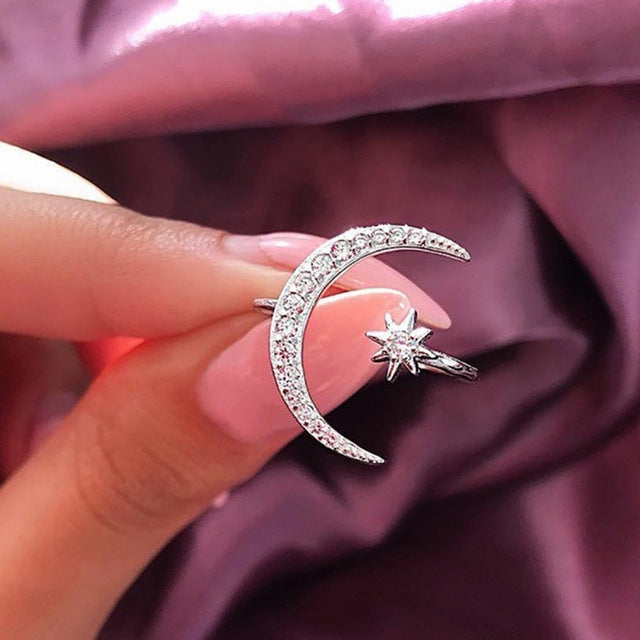 Crescent moon crystal ring with star charm, silver-tone sparkle texture on finger