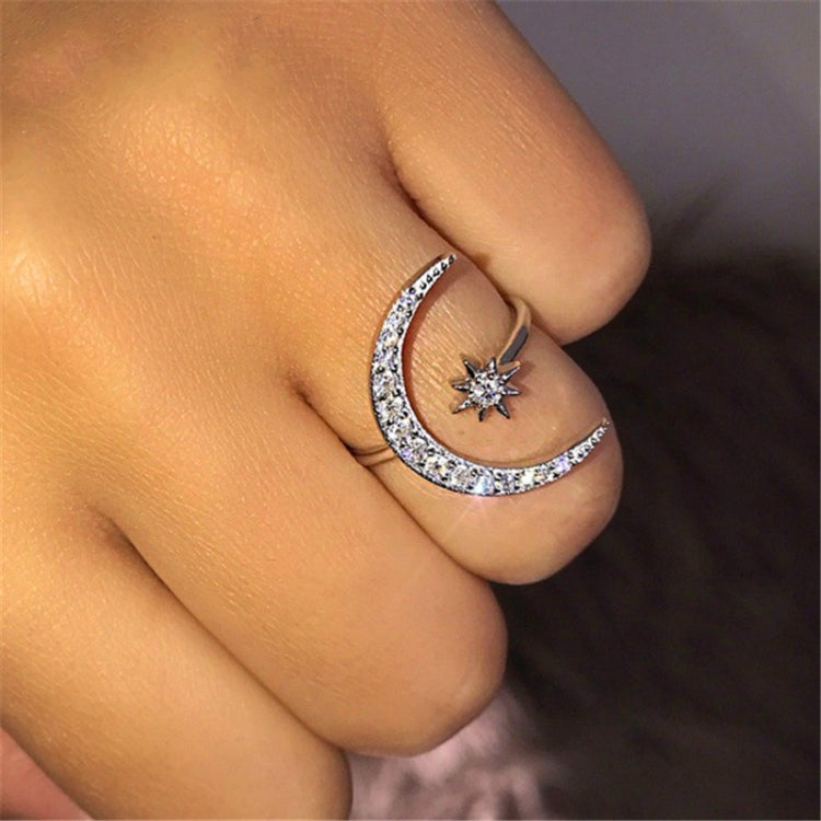 Silver-tone crescent moon crystal ring with star accent, close-up view on finger