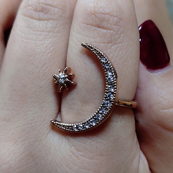 Silver-tone crescent moon crystal ring with star detail, close-up on finger