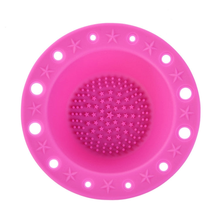 Hot pink silicone makeup brush cleaning bowl with central textured scrubbing pad and rim holes.