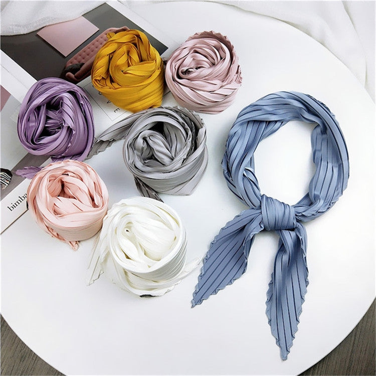 Assorted pleated silk square scarves in purple, yellow, pink, white, gray, and blue