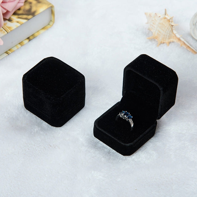 Black velvet ring jewelry box set, one closed and one open with silver-toned ring