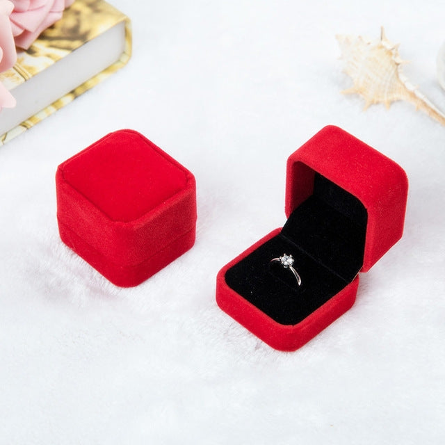 Red velvet ring jewelry box set, one closed and one open with silver-toned ring