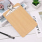 Wooden writing clipboard with metal clip holding papers and pen