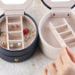 Open two-tier jewelry box with divided inserts for rings and earrings; hand lifts insert.