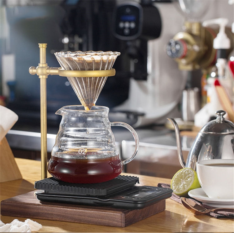 Brass coffee filter holder brewing stand with glass carafe on dark base