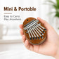 Brown mini kalimba thumb piano held in hand with silver metal keys