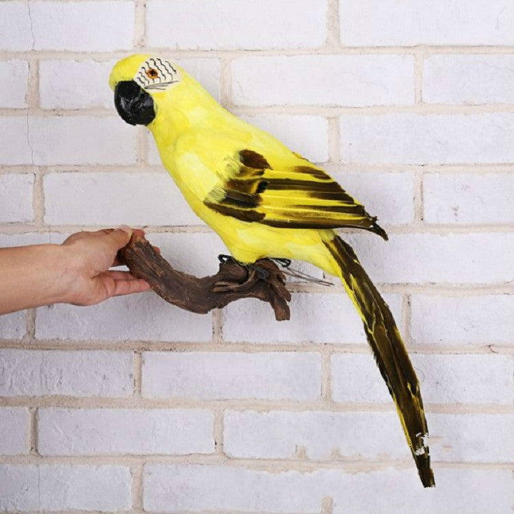 Yellow simulated parrot bird decoration with detailed beak and long tail on a branch