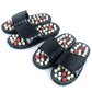 Pair of black massage slide sandals with acupoint studs in white and red