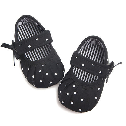 Infant black soft-sole crib shoes with white polka dots and striped lining, bow ties