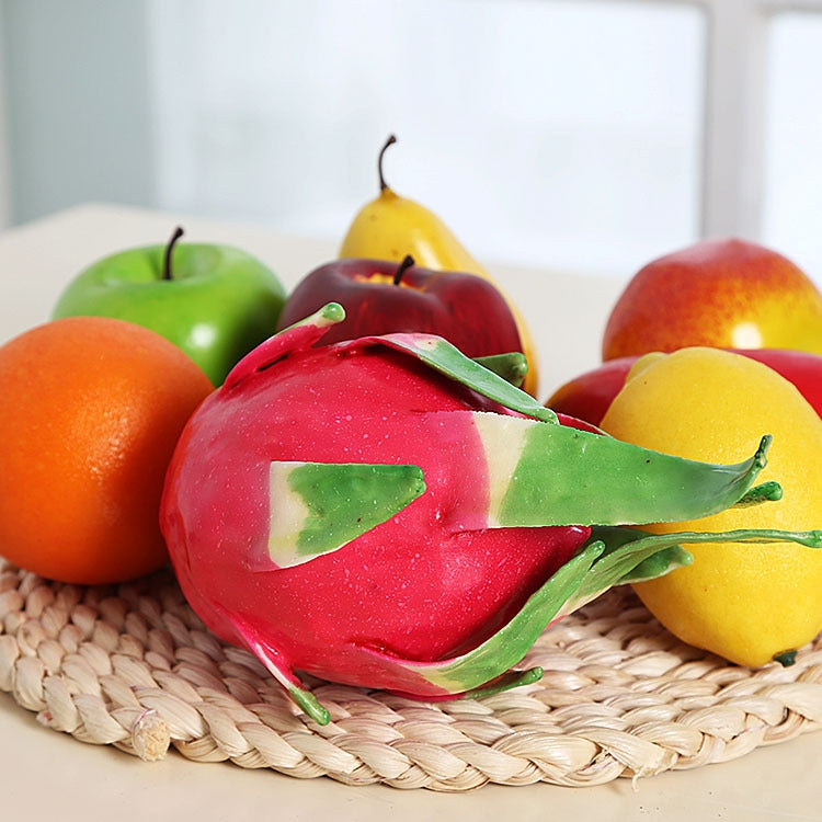 Red dragon fruit ornament with green leaves on a woven tray with faux fruit