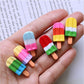 Ice cream stick resin cabochons in hand: yellow, pink, red and green striped