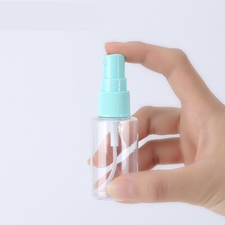 Mini clear empty bottle with teal spray top, held in a hand for travel use