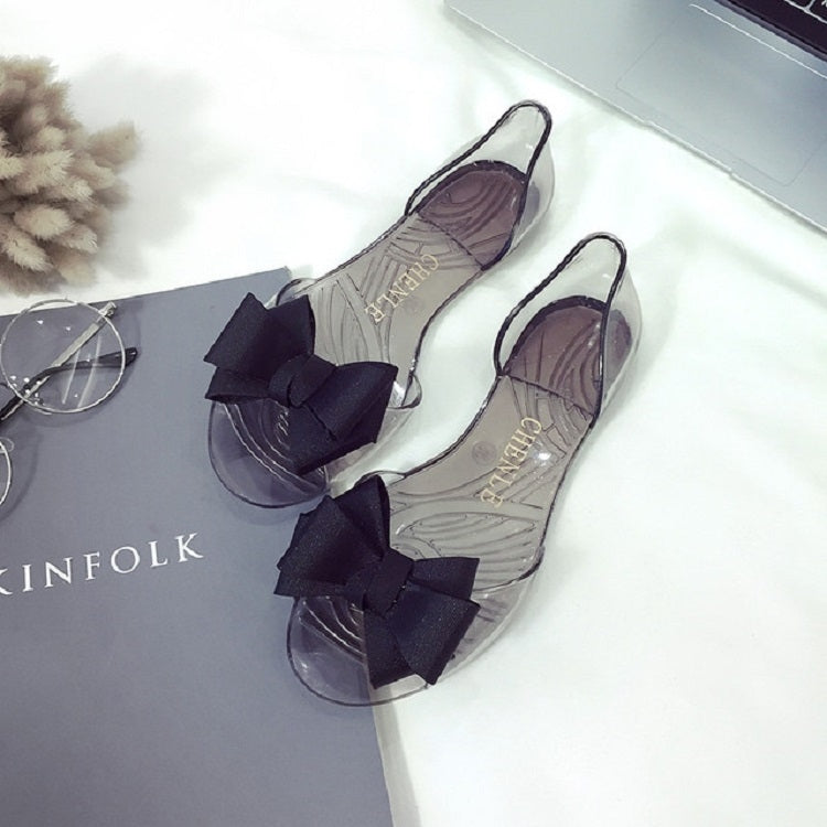 Transparent jellyfish-mouth flat shoes with dark bow ties and clear upper straps