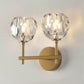 Gold double wall lamp with two faceted crystal shades and round backplate