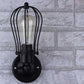 Wall lantern light with matte black cage frame, clear glass tube and lit Edison bulb