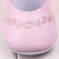 Baby girl first walker crib shoes close-up in pale pink with embroidered floral panel and stitching