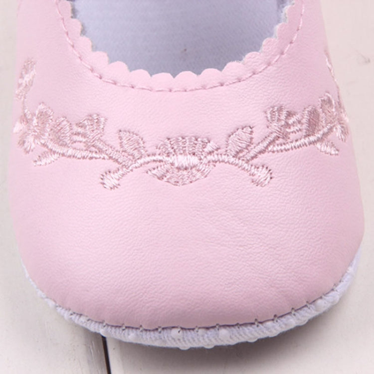 Baby girl first walker crib shoes close-up in pale pink with embroidered floral panel and stitching