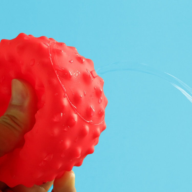 Red spiky rubber bath ball close-up with water droplets
