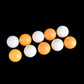 Seamed table tennis balls, orange and white, scattered on dark background