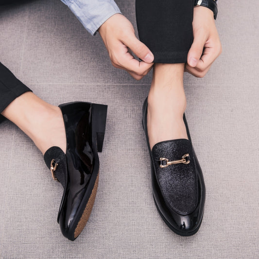 Pair of men's black pointed slip-on loafers with gold buckle ornament