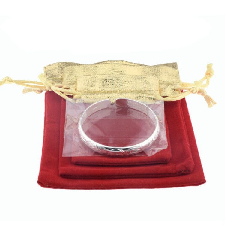 Red velvet drawstring jewelry pouch with top tie, showing a bracelet inside