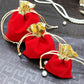 Red velvet drawstring jewelry pouches with gold bows and beige cords