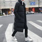 Men's black long puffer down jacket, button front, quilted insulation, standing side view