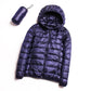 Navy blue hooded puffer jacket with quilted panels, zip front, and carry pouch