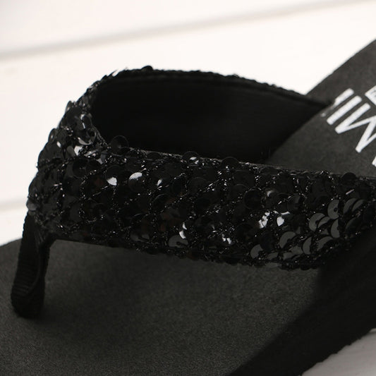 Close-up of a black sequin strap on a wedge flip-flop