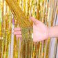 Gold holographic foil tinsel curtain with glitter strands, held in a hand.