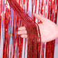 Red metallic foil tinsel curtain with glitter strands, held up in hand.