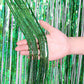 Laser rain tinsel foil curtain, green glitter strands tied at top, held in hand