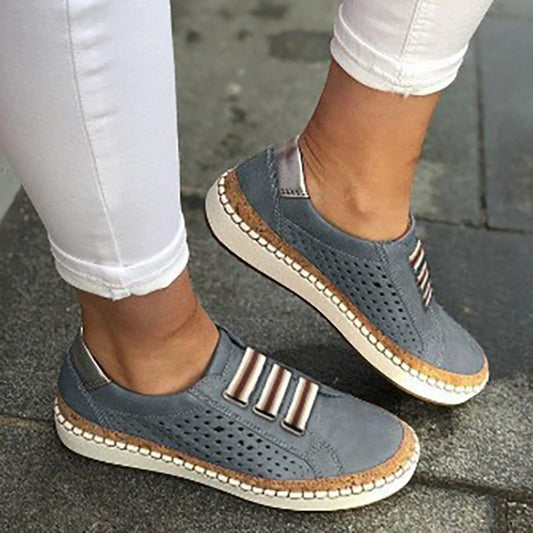 Blue slip-on sneakers with perforated upper, striped strap detail, and cream-colored sole