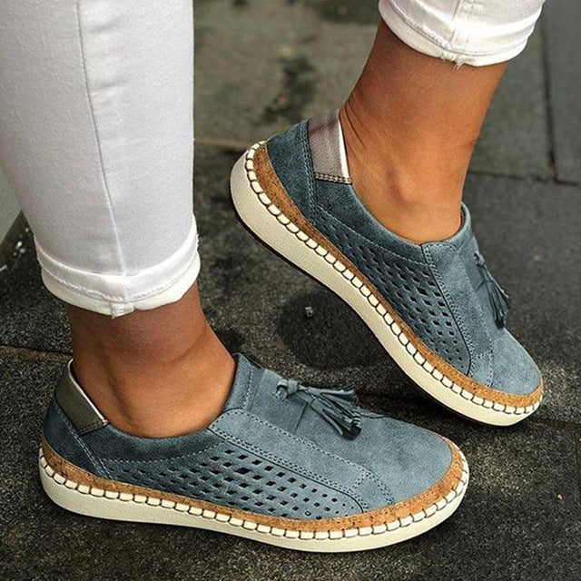 Teal blue perforated slip-on sneakers with tassel accent and white midsole on feet