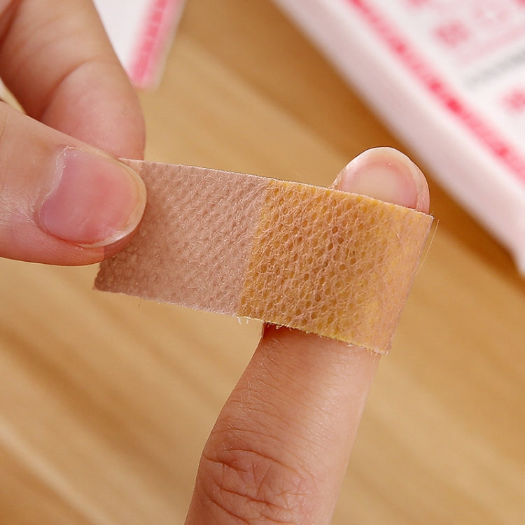 Waterproof adhesive medical bandage strip held on finger, tan porous pad and tape