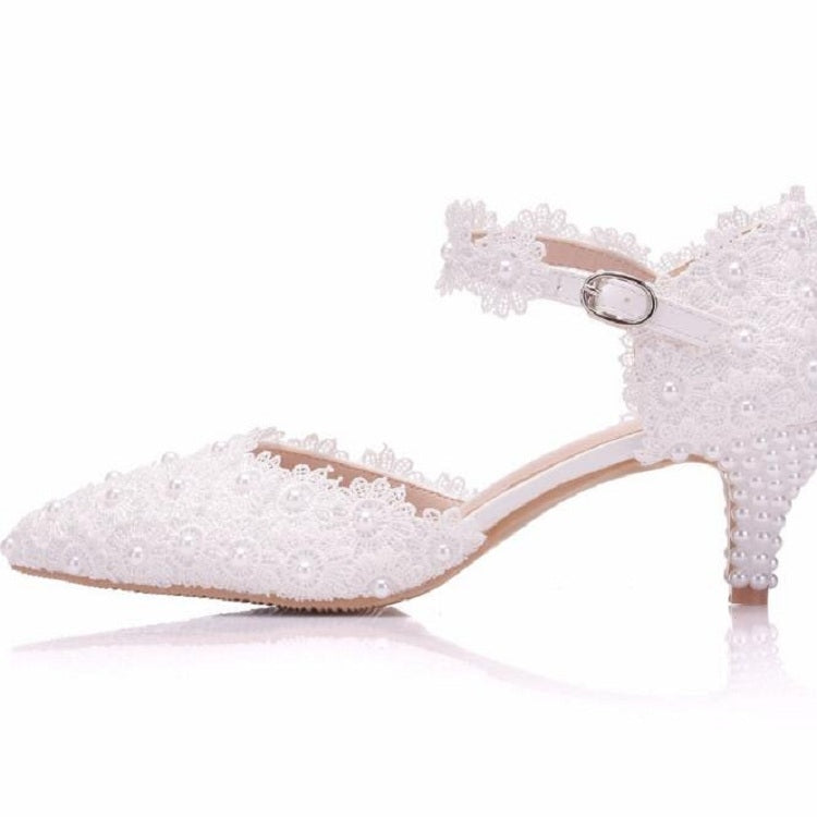 White lace pointed-toe heel with ankle strap, silver buckle, and beaded embellishments