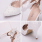 White lace pointed-toe heels with close-up of ankle strap buckle and beaded trim
